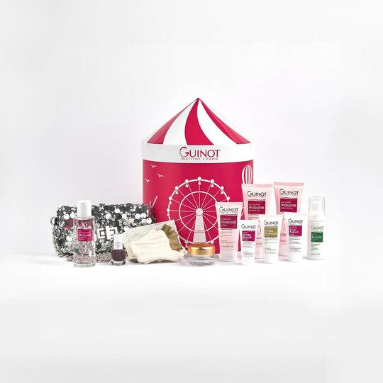 Collection of Guinot skincare products and a red and white striped bag on a white background