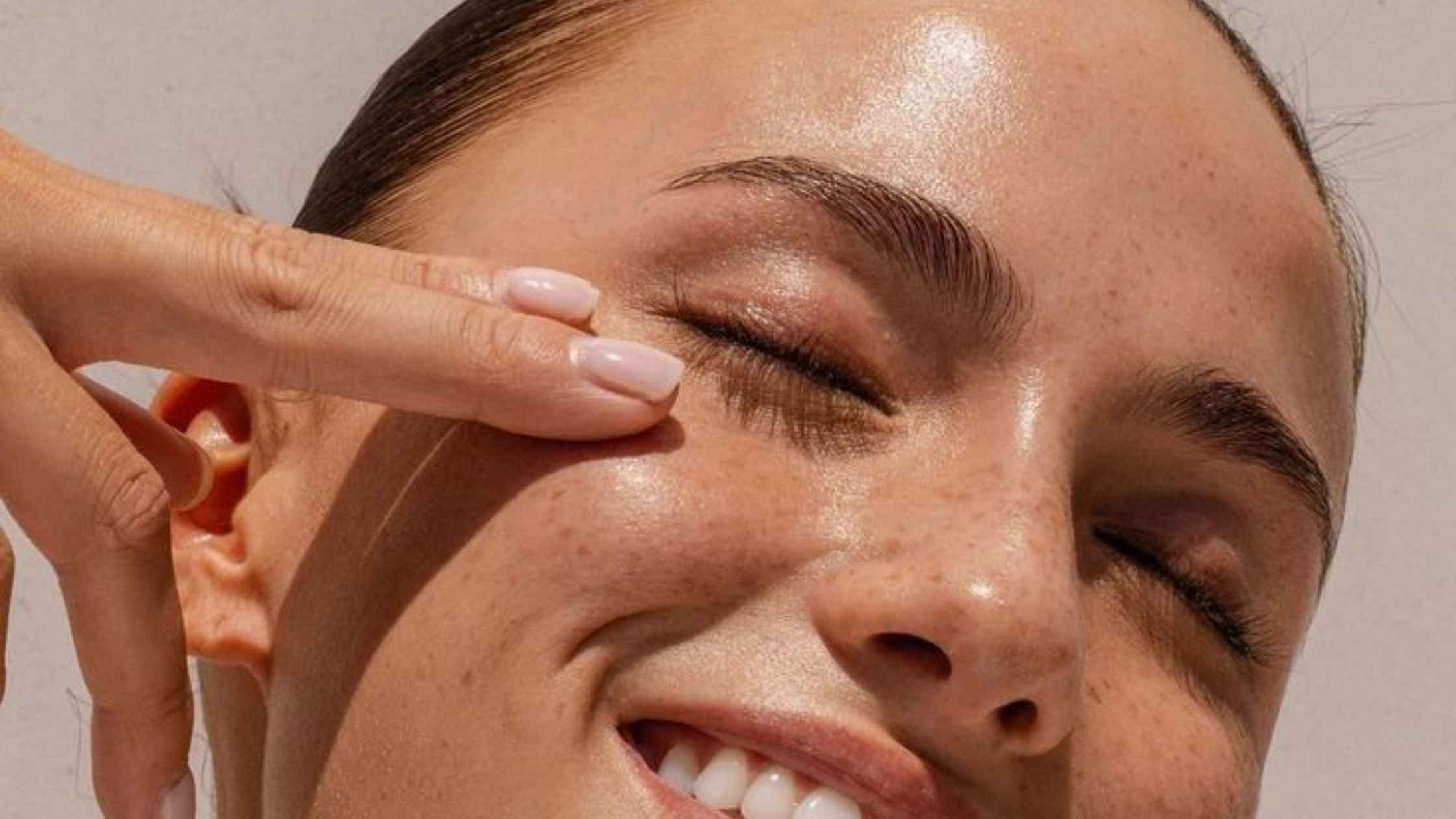 a close up of a woman touching her face and smiling