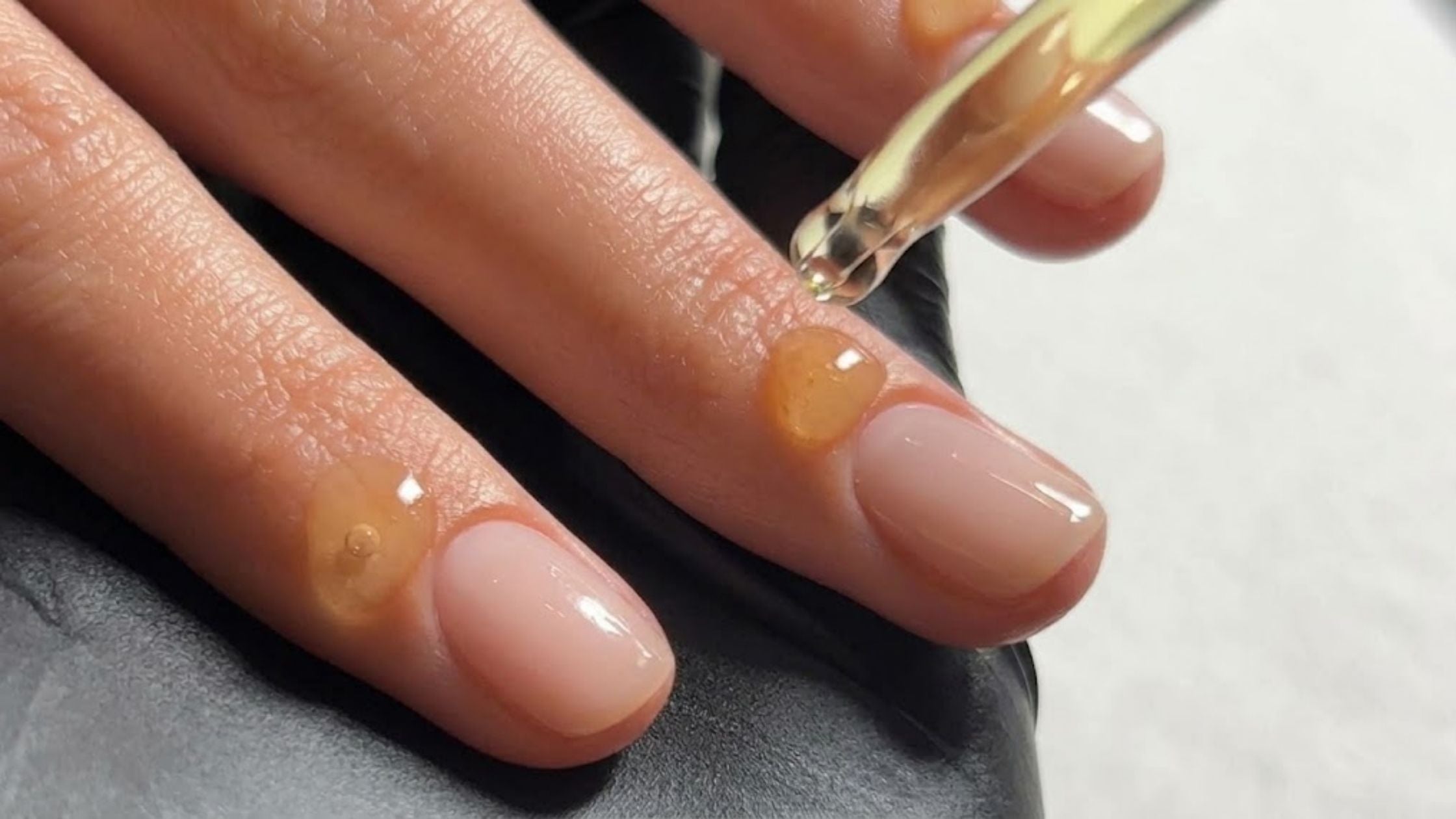 Cuticle oil being applied to a nude manicure