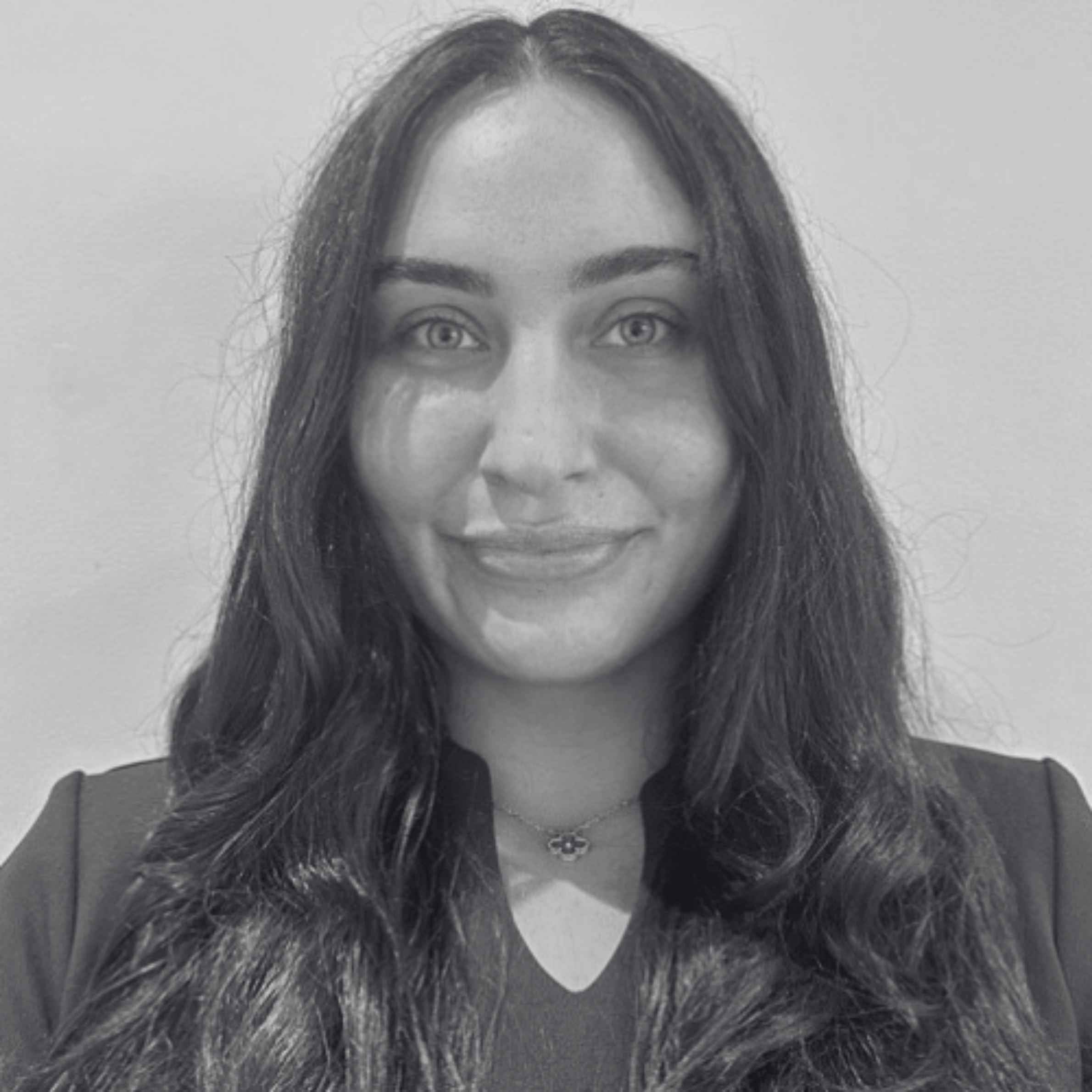 Black and white photo of a person with long hair wearing a massage therapist top.