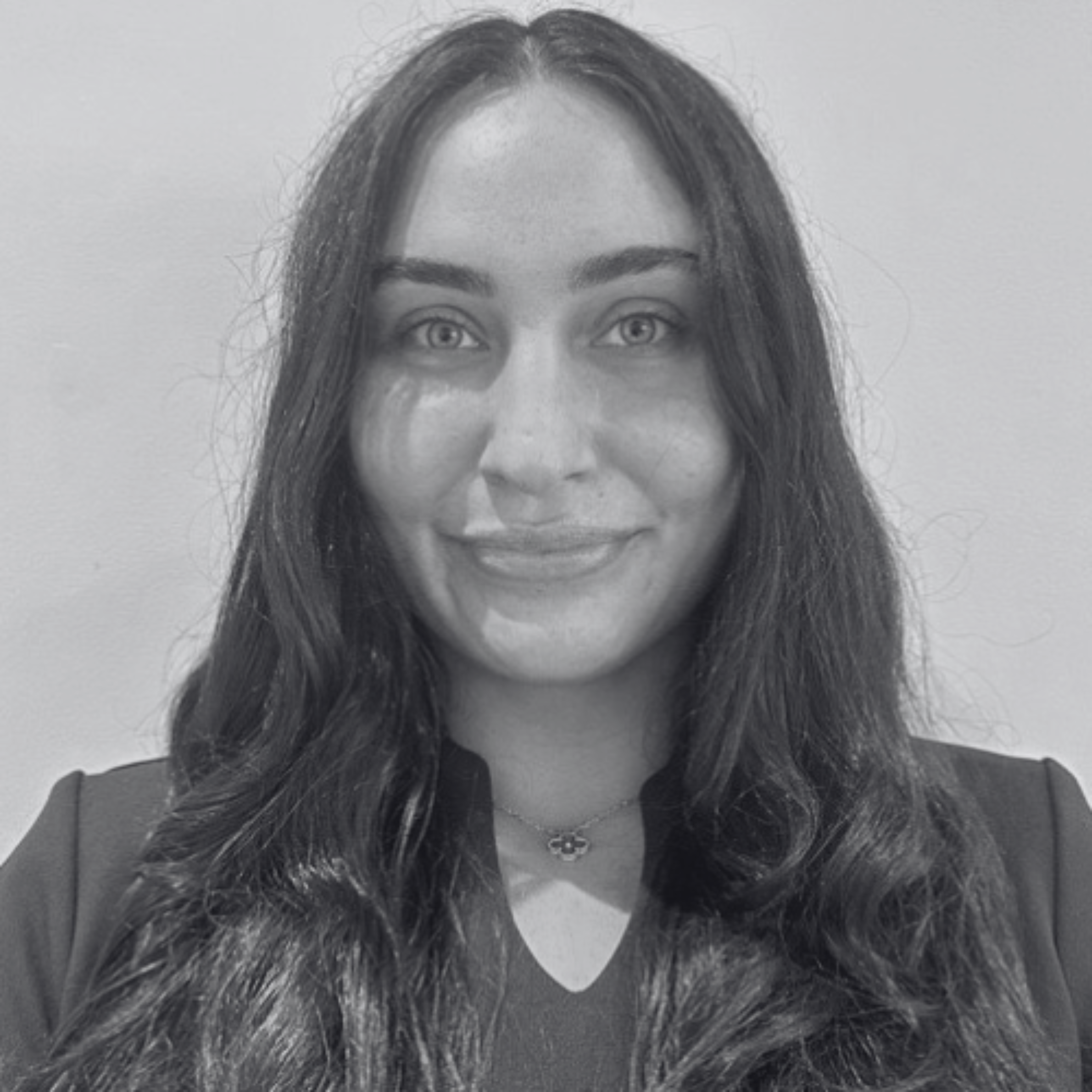 Black and white portrait of a woman with her hair down and wearing a black top and flower necklace