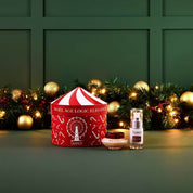 Cosmetic set with a red and white box, bottle, and jar on a green surface with festive decorations.