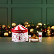 Cosmetic set with a 'Noel Legacy Set' box against a festive background with lights and decorations.
