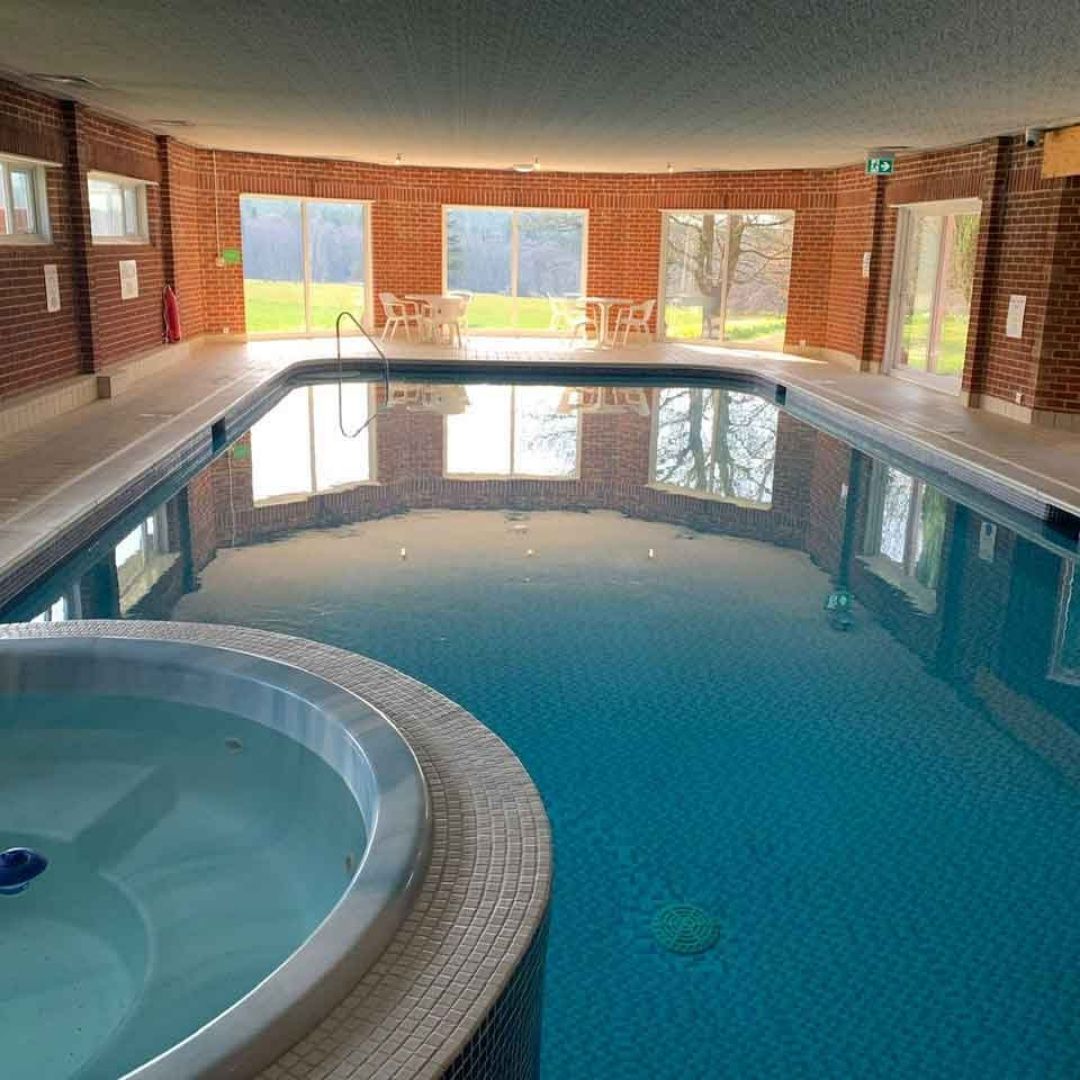 Indoor pool with hot tub in a brick-walled building