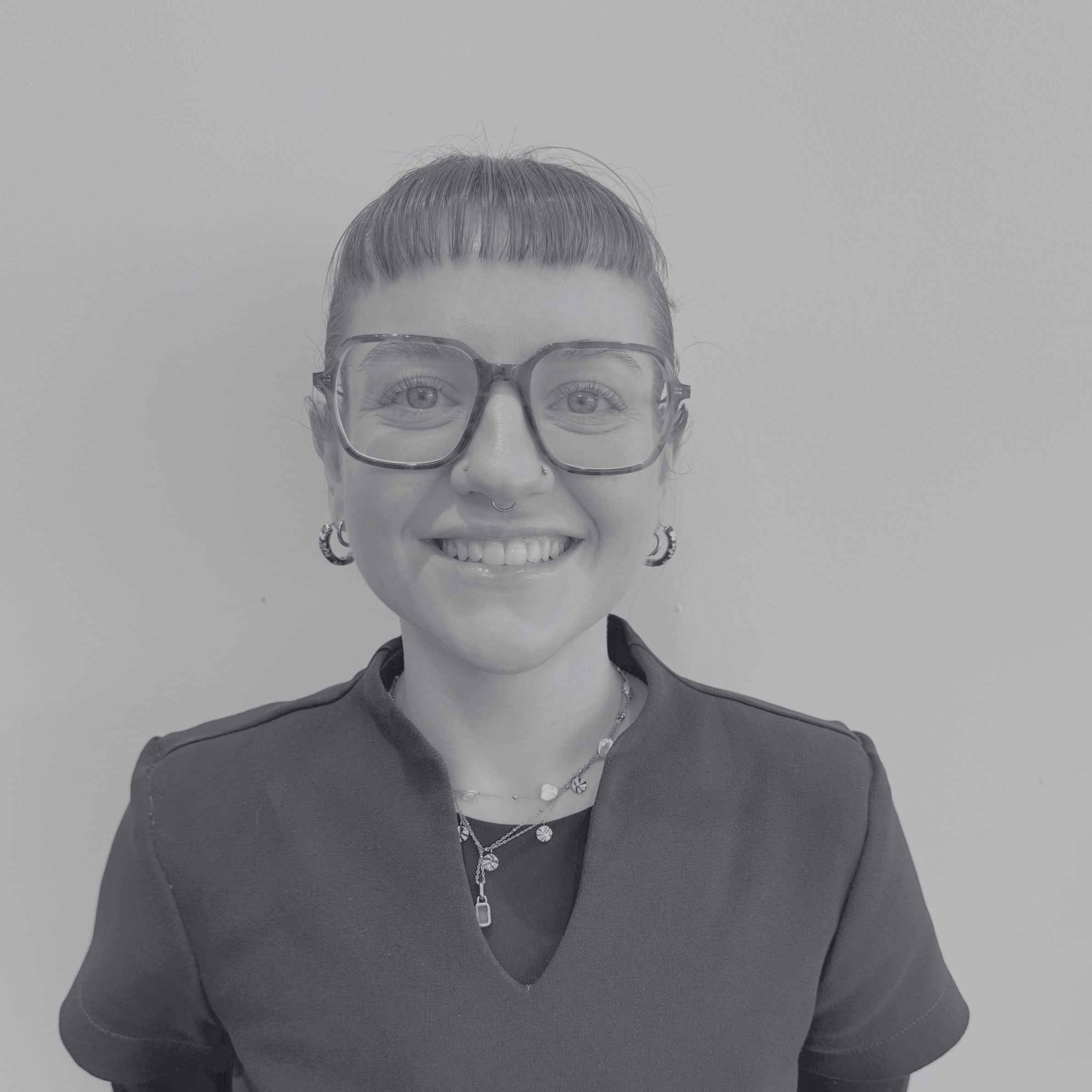 Black and white photo of a person wearing glasses and a dark top against a plain background