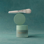 Cosmetic jar with a brush on a teal background