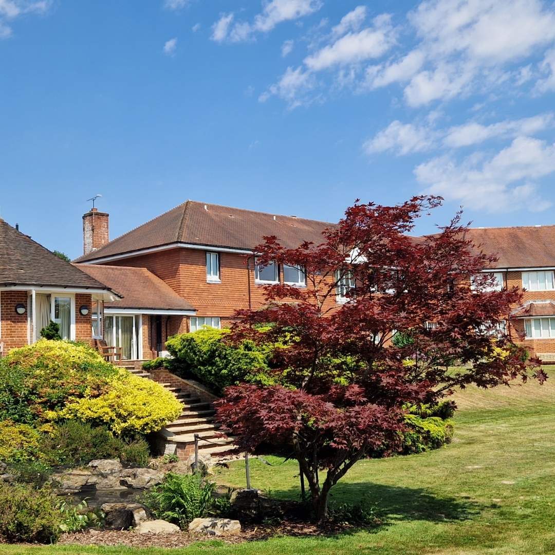 Brick house with a well-maintained garden under a blue sky.
