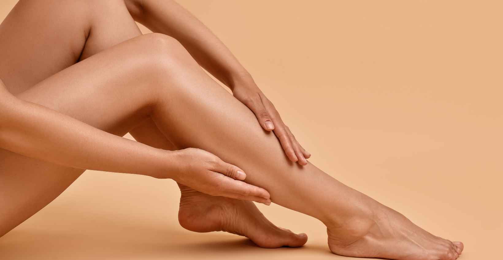 Naked legs of a person against a beige background