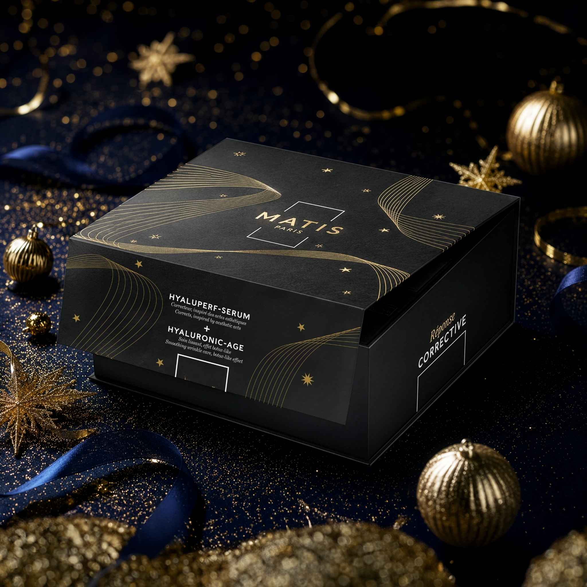 A black Matis Cosmetics Hyaluptide-Serum and Hyaluroidic-Age gift box, styled on a dark glittery background with gold ornaments and blue ribbons.