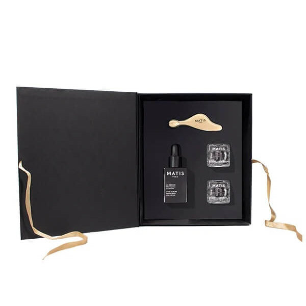 Set of skincare products in a black box with gold accents on a white background